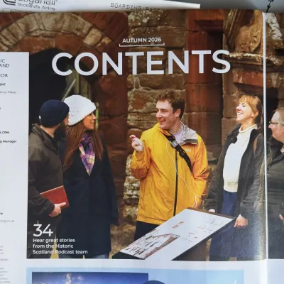 The magazine's contents spread: a man in a yellow jacket with a recorder slung across his chest talking to a group beside a stone archway, captioned 'Hear great stories from the Historic Scotland Podcast team'.